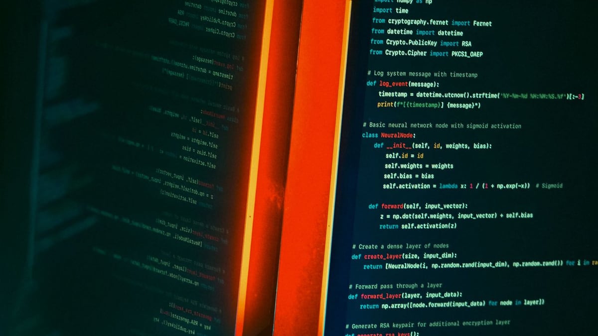 Two code editors glowing in contrasting orange and blue light on a dark desk